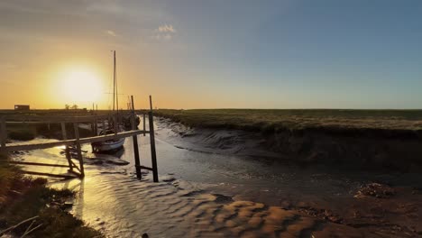 Small-sailing-boat-docked-in-the-estuary-with-evening-with-golden-sunlight