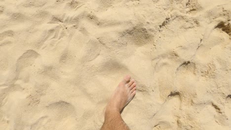 Feet-of-a-man-walking-on-the-beach-sand