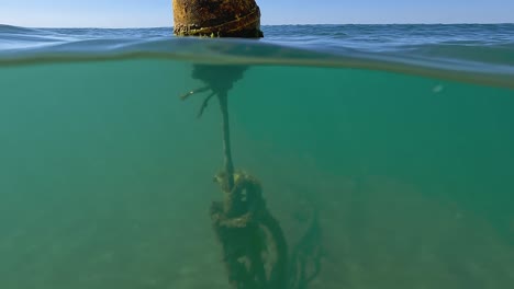 Half-underwater-tilt-up-view-of-isolated-yellow-floating-buoy-on-sea-water