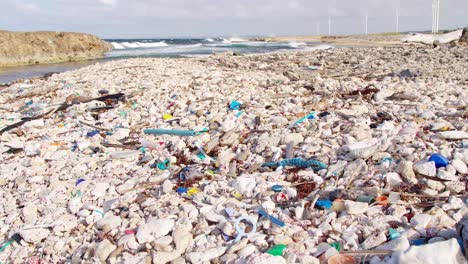 Tilt-of-man-made-plastic-debris-and-rubbish-slowly-being-washed-up-on-rocky-shore-in-the-Caribbean