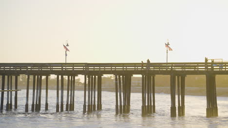 Schwenkaufnahme-Von-Menschen,-Die-Den-Ventura-Pier-Hinuntergehen,-Mit-Sonnenuntergang-Im-Hintergrund-In-Südkalifornien