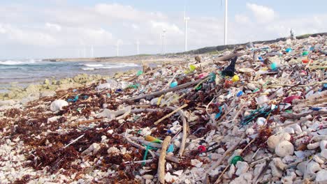 Static-wide-of-man-made-plastic-debris-and-rubbish-slowly-being-washed-up-on-rocky-shore-in-the-Caribbean
