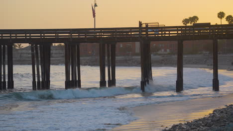Panning-shot-of-the-Ventura-Pier-with-bright-orange-sunset-in-the-background-located-in-Southern-California