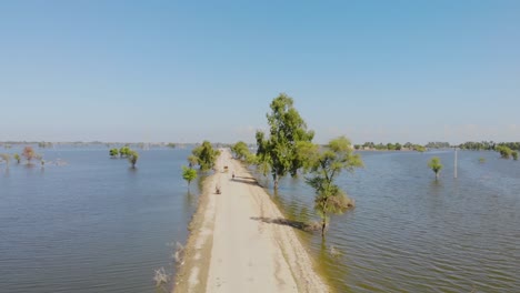 Aerial-Ascending-Shot-From-Empty-Road-Surrounded-By-Flood-Waters-In-Jacobabad,-Sindh