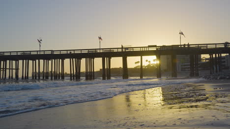 Dolly-Schuss,-Der-Sich-Rückwärts-Entlang-Des-Ventura-Strandes-Bewegt,-Mit-Dem-Pier-Mit-Sonnenuntergang-Im-Hintergrund-In-Südkalifornien