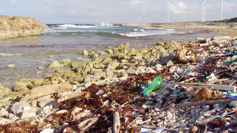 Amplia-Inclinación-Hacia-Arriba-De-Desechos-De-Basura-De-Plástico-Esparcidos-En-Una-Playa-Rocosa-En-El-Caribe