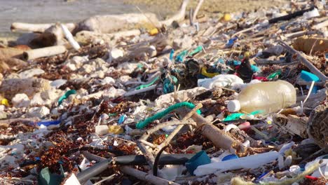 Close-up-pan-of-plastic-trash-debris-littered-on-rocky-beach-in-Caribbean