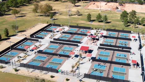 A-field-of-pickleball-courts-in-a-city-park-during-a-tournament---ascending-aerial-view