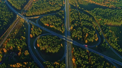 Ein-Großer-Autobahn-Kleeblatt-Austausch-In-Einer-Bewaldeten-Umgebung-Im-Herbst---Zeitraffer-Aus-Der-Luft