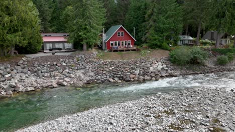 Drone-shot-of-multiple-private-cabins-lining-the-bank-of-the-Skykomish-River