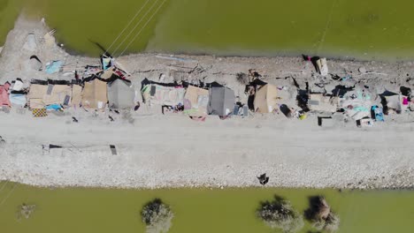 Aerial-Top-Down-View-Over-Elevated-Strip-Of-Land-Housing-Makeshift-Tents-Of-Surrounded-By-Flooded-Landscape-In-Jacobabad,-Sindh