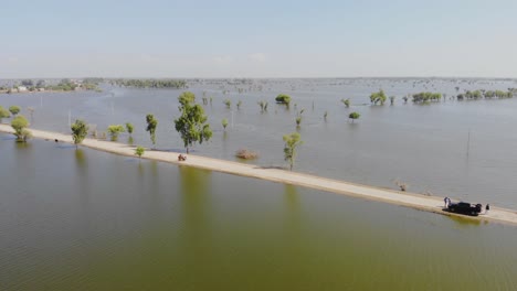 Vista-Aérea-De-Una-Carretera-Solitaria-Rodeada-De-Aguas-Inundadas-En-El-Horizonte-En-Jacobabad,-Sindh