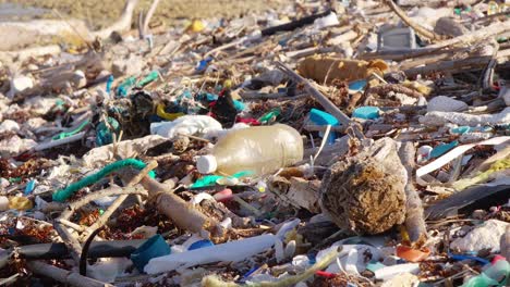 Close-up-tilt-of-plastic-trash-debris-littered-on-rocky-beach-in-Caribbean