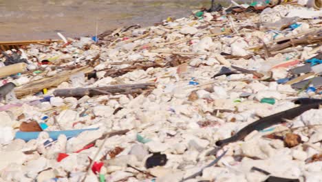 Pfanne-Von-Menschengemachten-Plastikabfällen-Und-Müll,-Die-Langsam-An-Der-Felsigen-Küste-In-Der-Karibik-Angespült-Werden