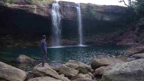 young-man-enjoying-the-natural-waterfall-falling-from-mountain-top-at-morning-video-taken-at-krangsuri-waterfall-meghalaya-india