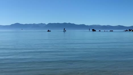 Silhouettes-of-people-kayaking-and-paddle-boarding-at-Sand-Harbor-State-Beach-in-Incline-Village,-Nevada