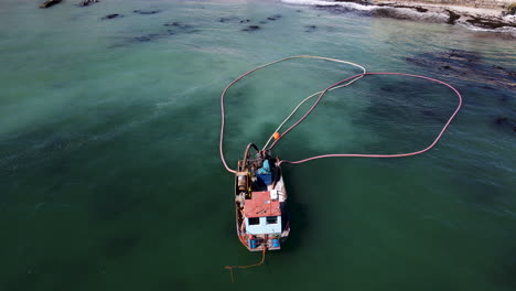 Aerial-shot-of-anchored-diamond-boat-with-its-floating-pipes
