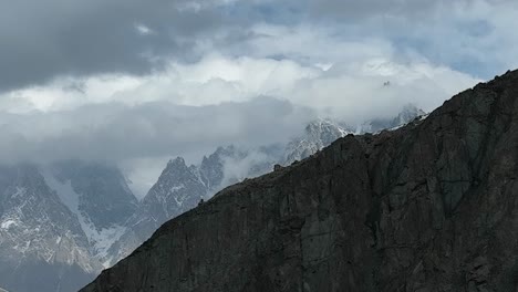 Aerial-Rising-Behind-Mountain-Wall-To-Reveal-Passu-Cones-In-the-Karakoram-Range-Hiding-In-Clouds