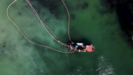 Overhead-view-of-diamond-diving-boat-with-floating-pipes-next-to-jetty