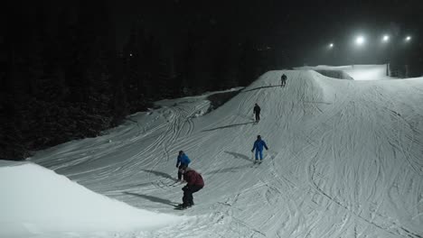 4K-Zeitlupe-Einer-Gruppe-Von-Skifahrern-Und-Snowboardspringen-Auf-Einem-Mittelgroßen-Schneehügel-Im-Funpark-Bei-Nacht-Im-Skigebiet-In-Norwegen
