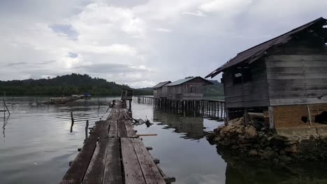 Caminando-Sobre-Una-Plataforma-De-Madera-Con-Un-Niño-Pescando-En-Misool,-Raja-Ampat,-Indonesia,-Asia