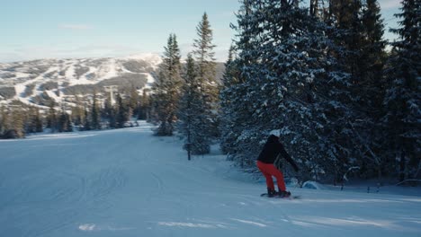 4K-Tracking-Einer-Snowboarderin,-Die-An-Einem-Sonnigen-Wintertag-In-Norwegen-Bergab-Geht