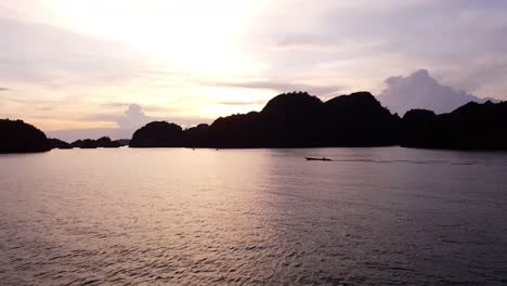 Sunset-with-a-moving-boat-against-hills-in-Misool,-Raja-Ampat,-Indonesia,-Asia