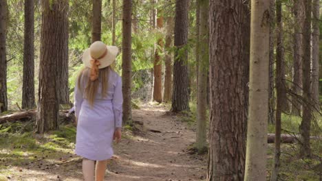 Blond-Young-Woman-Walking-the-Forest-Road-in-Casual-Purple-Dress