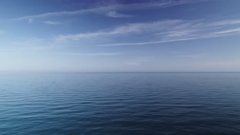Calm-and-emtpy-blue-ocean-with-scattered-clouds,-moving-backwards