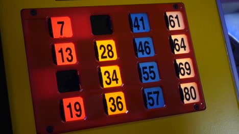 Nahaufnahme-Einer-Bingo-Maschinenkarte,-Die-In-Einer-Unterhaltung-Mit-Einem-Jungen-Mädchen,-Das-Das-Spiel-Spielt,-Beleuchtet-Ist
