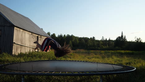 Kid-flips-on-a-trampoline-with-an-old-barn-in-the-background