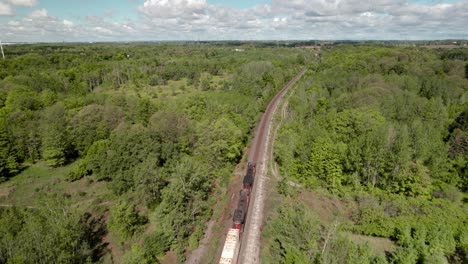 Diesel-Güterzug-Fährt-Durch-Eine-üppig-Grüne-Waldlandschaft-Mit-Strahlendem,-Sonnigem-Himmel