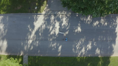 Man-walking-his-white-dog-in-neighborhood-aerial-view-high-cinematic-angle