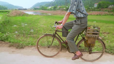 View-of-a-farmer-paddling-his-bicycle-on-a-cloudy-day-surrounded-by-rice-fields-on-a-hilly-terrain-in-Lang-Son-city,-Vietnam