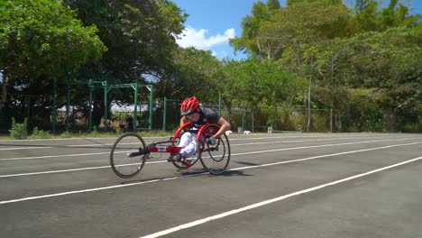 A-kid-with-disability-driving-a-handbike-at-a-paracycling-race,-using-his-strength-to-overcome-the-difficulty