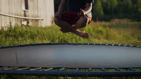Closeup-of-a-kid-springing-in-slowmotion-on-a-trampoline-while-in-a-lotus-position