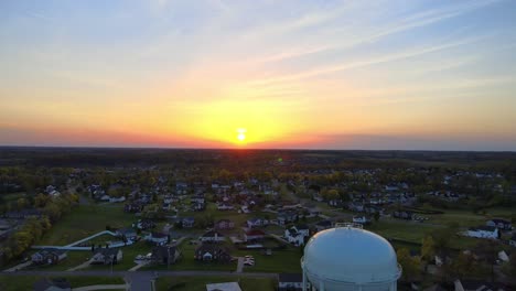 Beautiful-aerial-sunset-over-suburban-neighborhood-with-water-tower-in-forefront