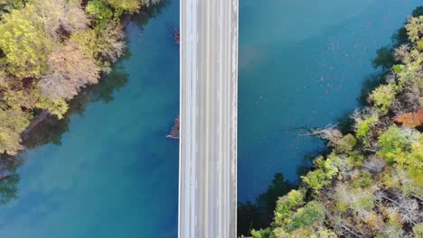 Aerial-top-down-shot-of-a-bridge-over-a-green-blue-river
