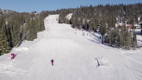 4K-aerial-drone-of-snowboarder-jumping-in-the-snow-on-fun-park-piste-on-a-sunny-day-in-a-ski-resort-in-Norway