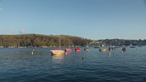 Small-Sail-Boats-Docked-In-Fowey-Harbour-with-Scenic-Coast-Landscape-of-Polruan-in-Background--wide-shot