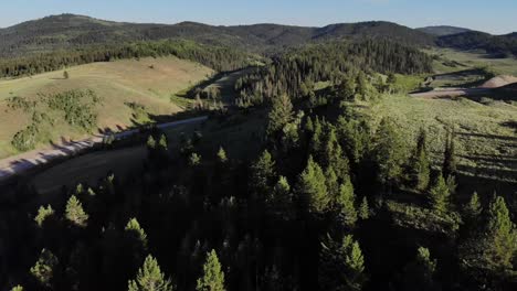 Drone-comes-over-a-forest-covered-hill-with-long-shadows