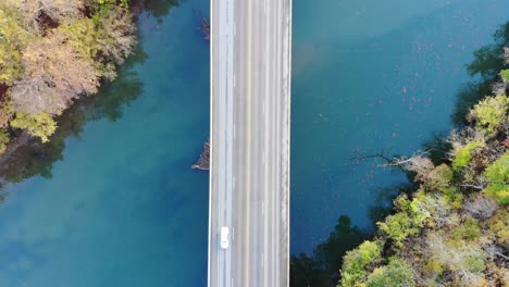 Aerial-top-down-shot-of-a-bridge-over-a-green-blue-river