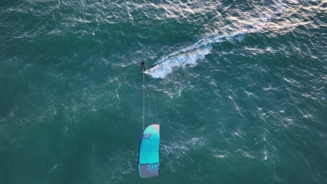 Aerial-birdseye-view-of-a-kite-surfer-off-the-coast-of-Cape-Town-in-South-Africa-at-sunset-in-with-waves