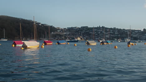 Wooden-Sail-Boats-Glow-in-Evening-Sunshine-Moored-in-Fowey-Harbour,-Cornwall,-England---Wide-Shot