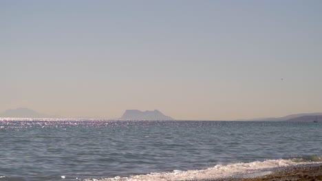 Silhouette-of-Rock-of-Gibraltar-in-distance-from-ocean-beach