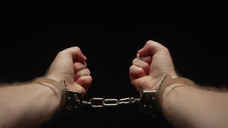 Man-unsuccessfully-attempting-to-break-free-from-handcuffs