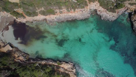 Luftaufnahme-Von-Oben-Nach-Unten-über-Wunderschönes-Türkisfarbenes-Wasser-An-Der-Felsigen-Küste-Mallorcas