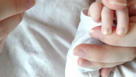 Newborn-infant-baby,-father-mother-cutting-tiny-hands,-closeup-high-angle,-interior-bed