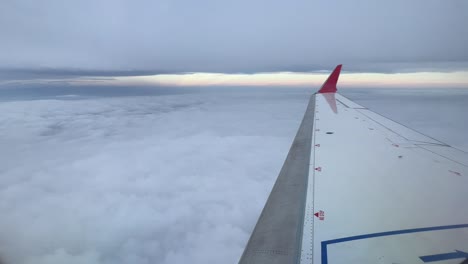 Right-jet-wing-with-red-winglet-while-flying-between-layers-of-clouds