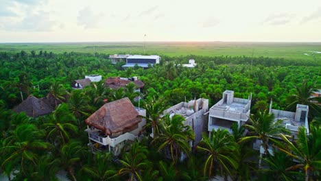 Aerial-Footage-Of-Lush-Green-Jungle-Rainforest-Hotels-And-Buildings-With-Dreamy-Sunset-in-the-Background